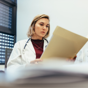 Doctor sitting at desk reading documents.