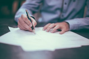 Man signing papers at table.